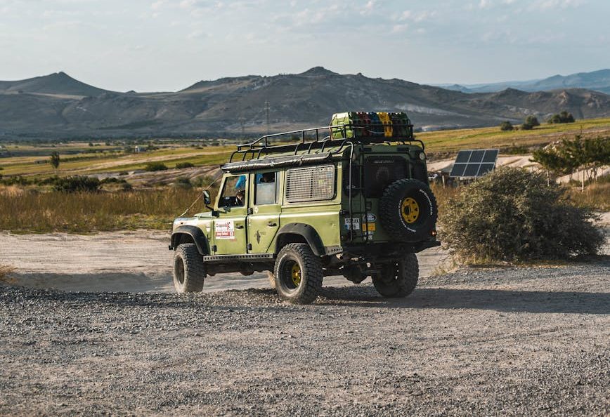 green jeep parked on dirt road