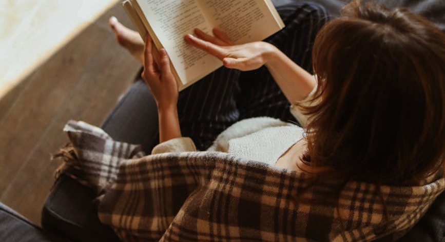 woman sitting on a sofa and reading a book
